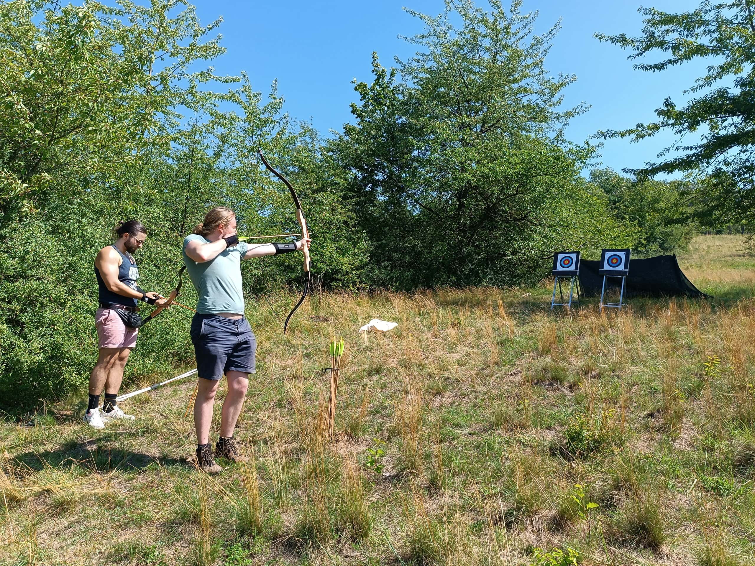 Hannes und Björn mit Bogen beim Bogenschießen draußen.