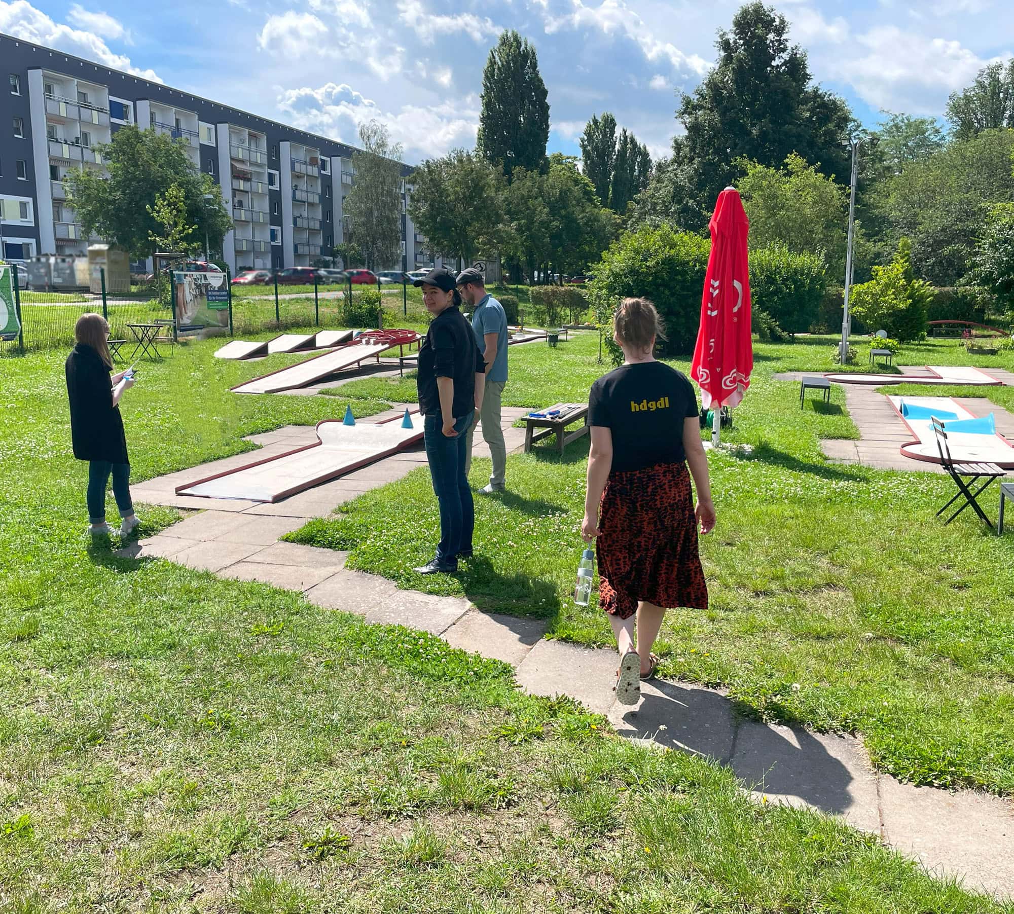 Hupa Teamevent Minigolf 2 Unser Team ist um eine Minigolfbahn versammelt und schaut Jens W. beim ersten Schlag zu.