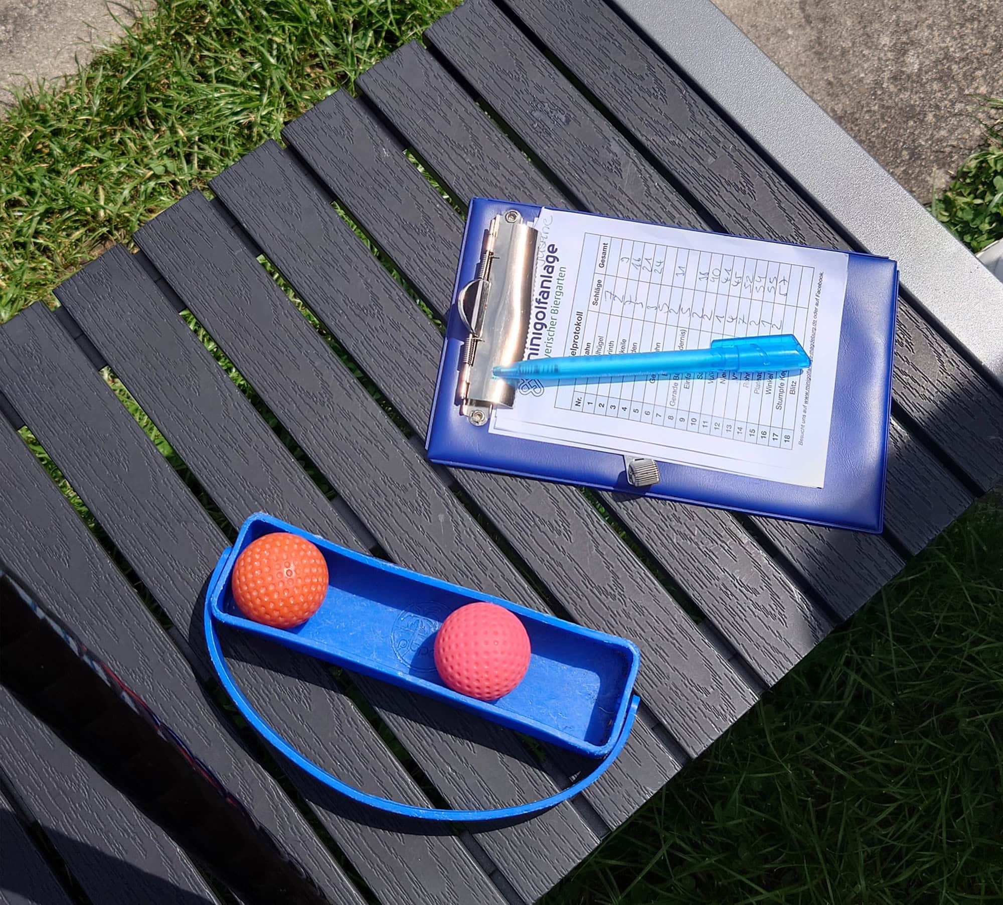 Hupa Teamevent Minigolf 5 Auf einer Bank liegen Golfbälle und das Protokoll mit den Ergebnissen vom Minigolf.