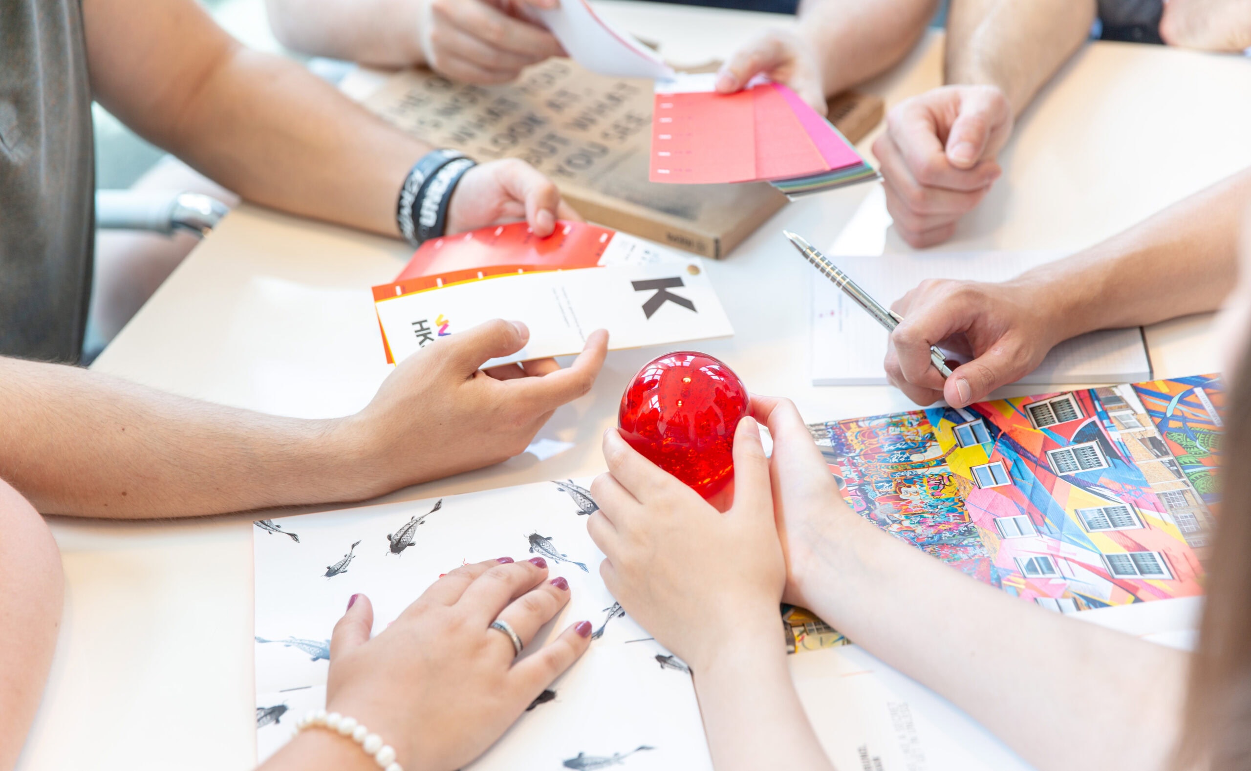 Ausschnitt von Händen, die auf einem Tisch mit Werbematerial arbeiten