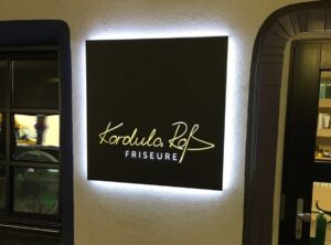 Designte Leuchtreklame für Kordula Roß Friseure hängt an der Wand