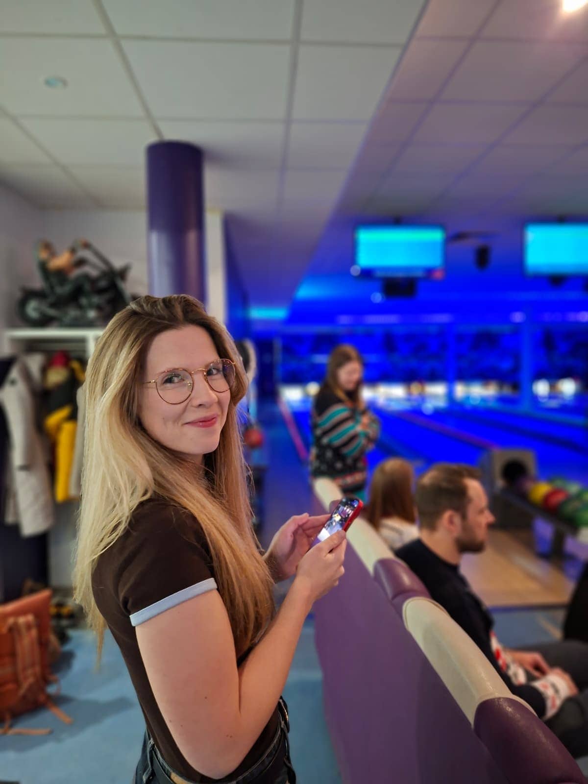 Weihnachtsfeier 2025 – Franzi Franzi steht in der Bowlinghalle im LuckyFitness, Smartphone in der Hand für Social Media Aufnahmen