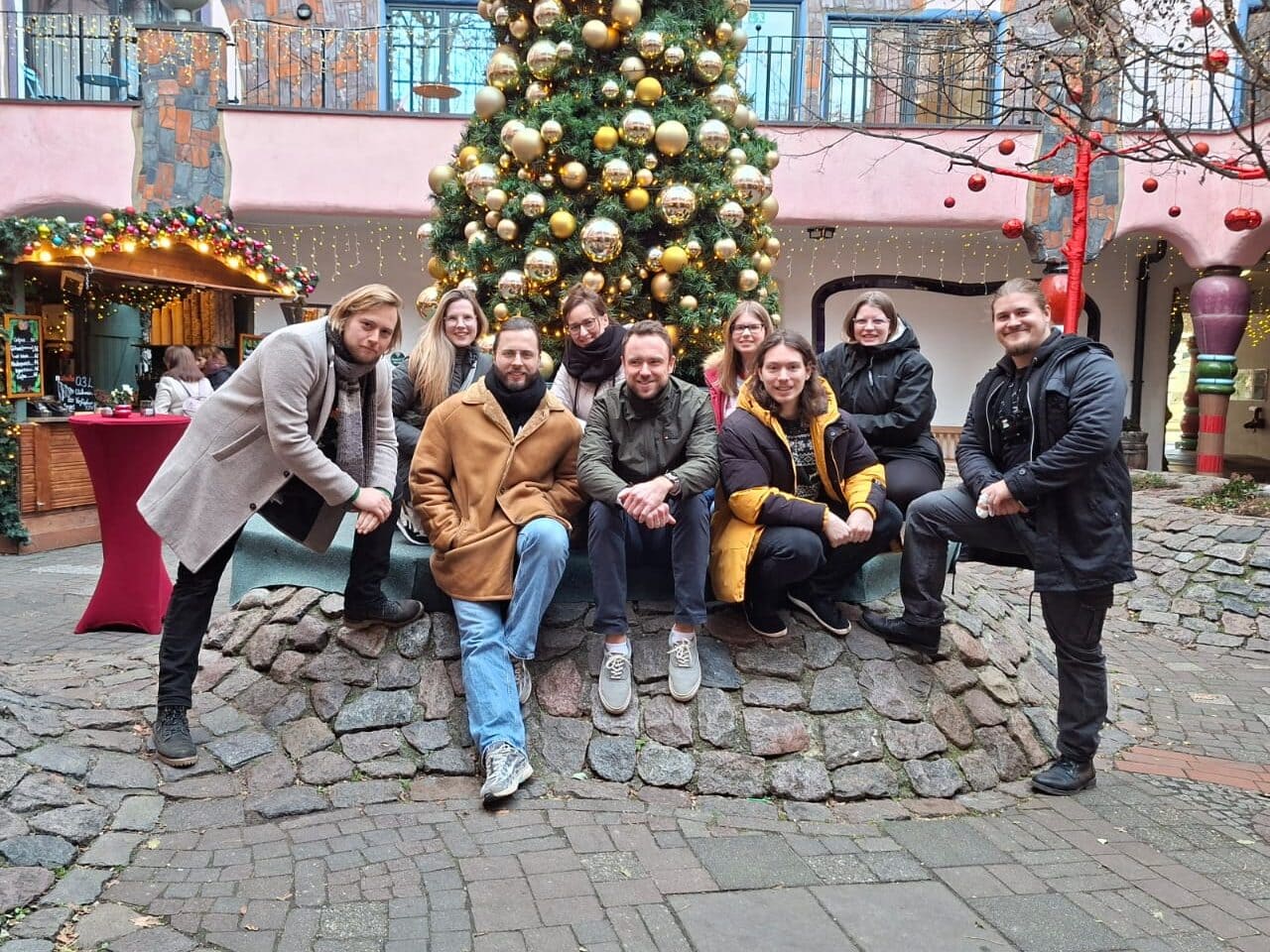 Hupa-Team Weihnachtsfeier 2025 Ein Gruppenfoto vom hupa Team vor dem Weihnachtsbaum im Hundertwasserhaus