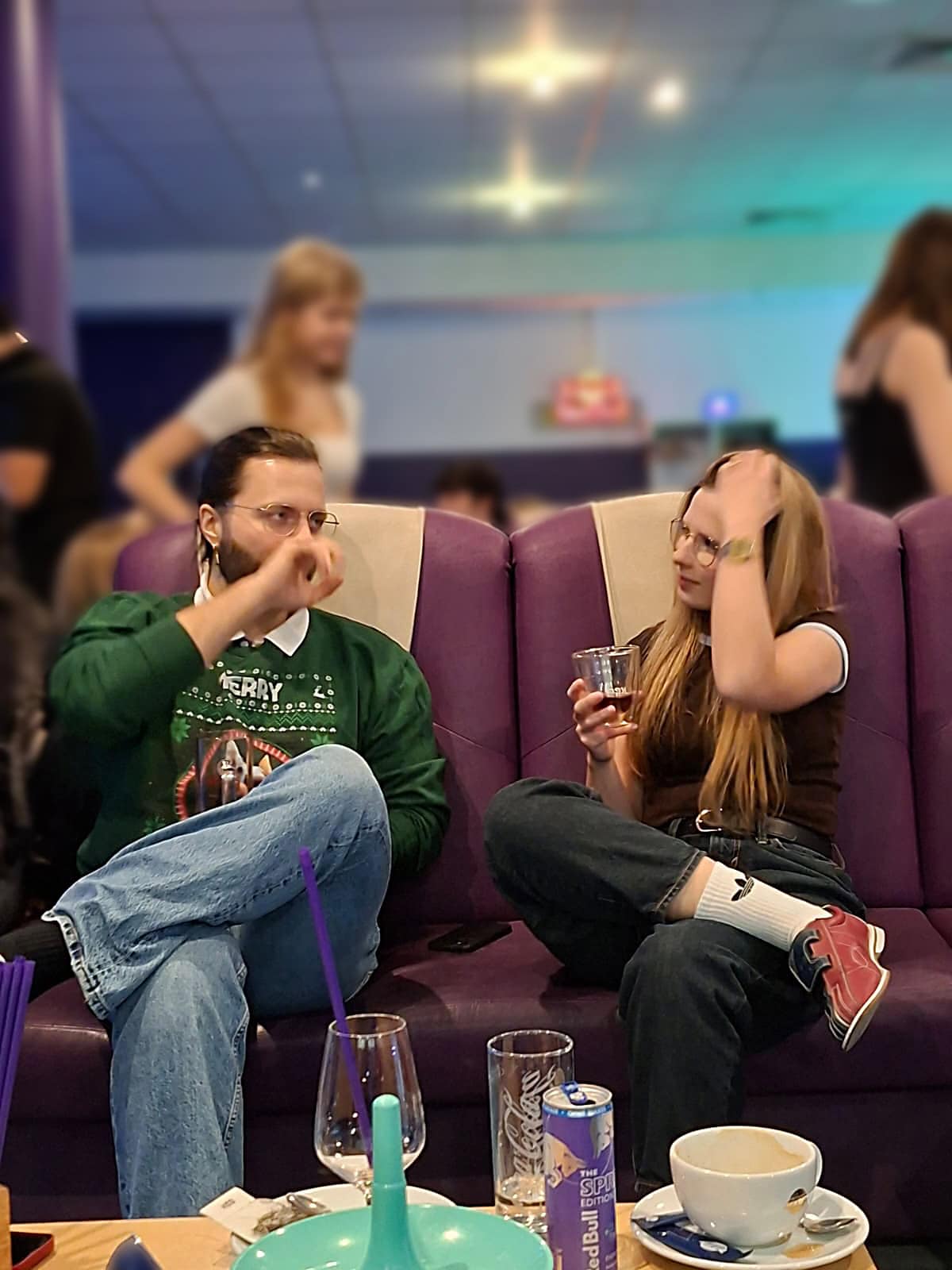 Weihnachtsfeier 2025 – Hannes und Franzi Hannes und Franzi sitzen auf dem Sofa in der Bowlinghalle und unterhalten sich angeregt