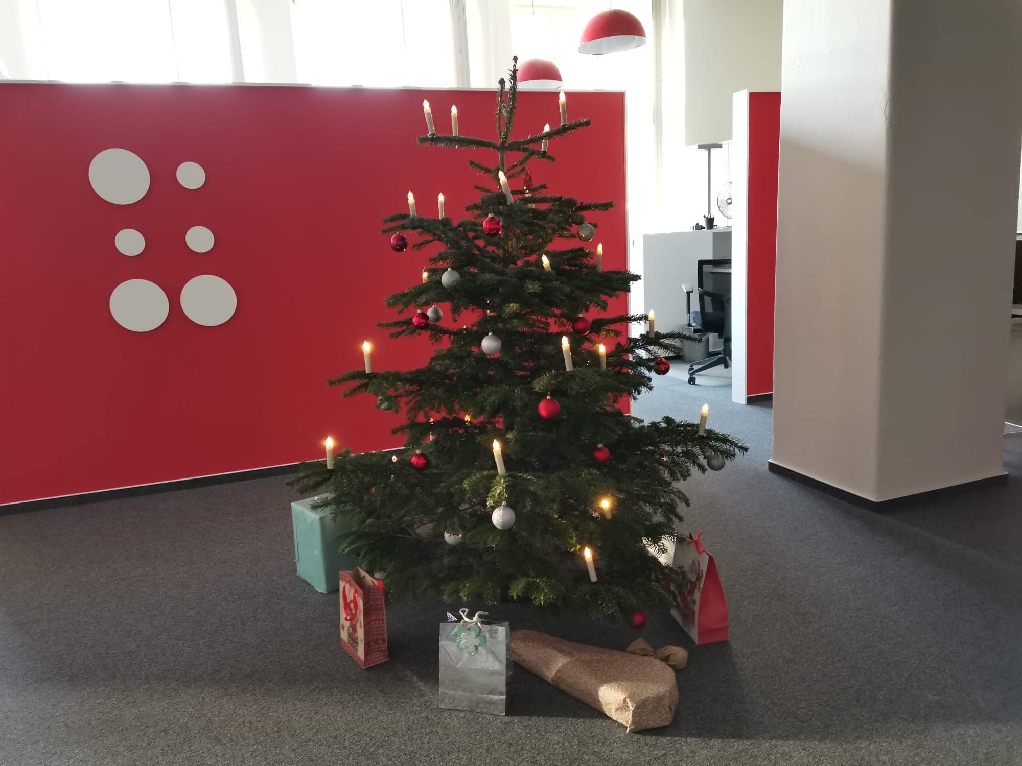 Hupa Weihnachtsbaum 2025 Geschmückter Weihnachtsbaum im Büro. Wichtelgeschenke liegen darunter