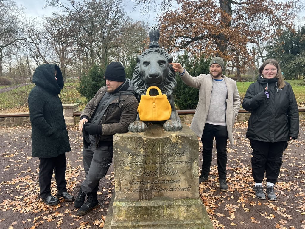 Team 1 posiert im Herrenkrug-Park vor der Löwenstatue