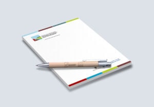 Schreibblock im Corporate Design der LAG USP. Darauf liegt ein hölzener Kugelschreiber worauf das Logo gedruckt ist.